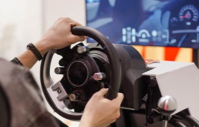 Image of a student trying to drive a simulator, representing options for car training in Guwahati.